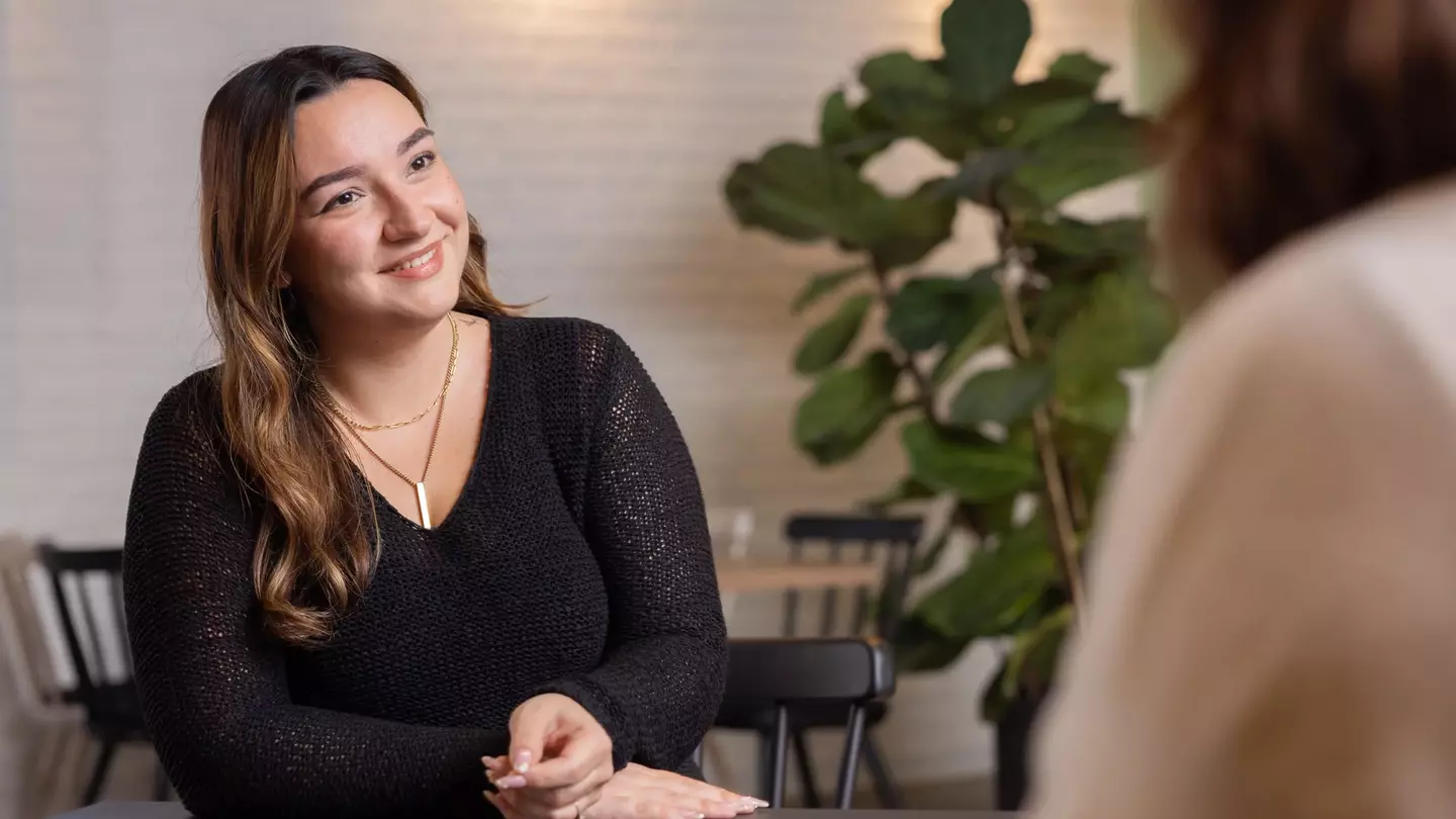 Eine Frau sitzt in einer modernen Lounge und lächelt
